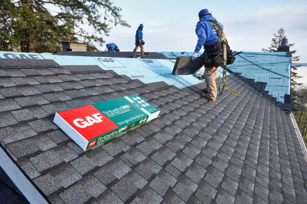 Roofers installing GAF shingles on a residential roof.